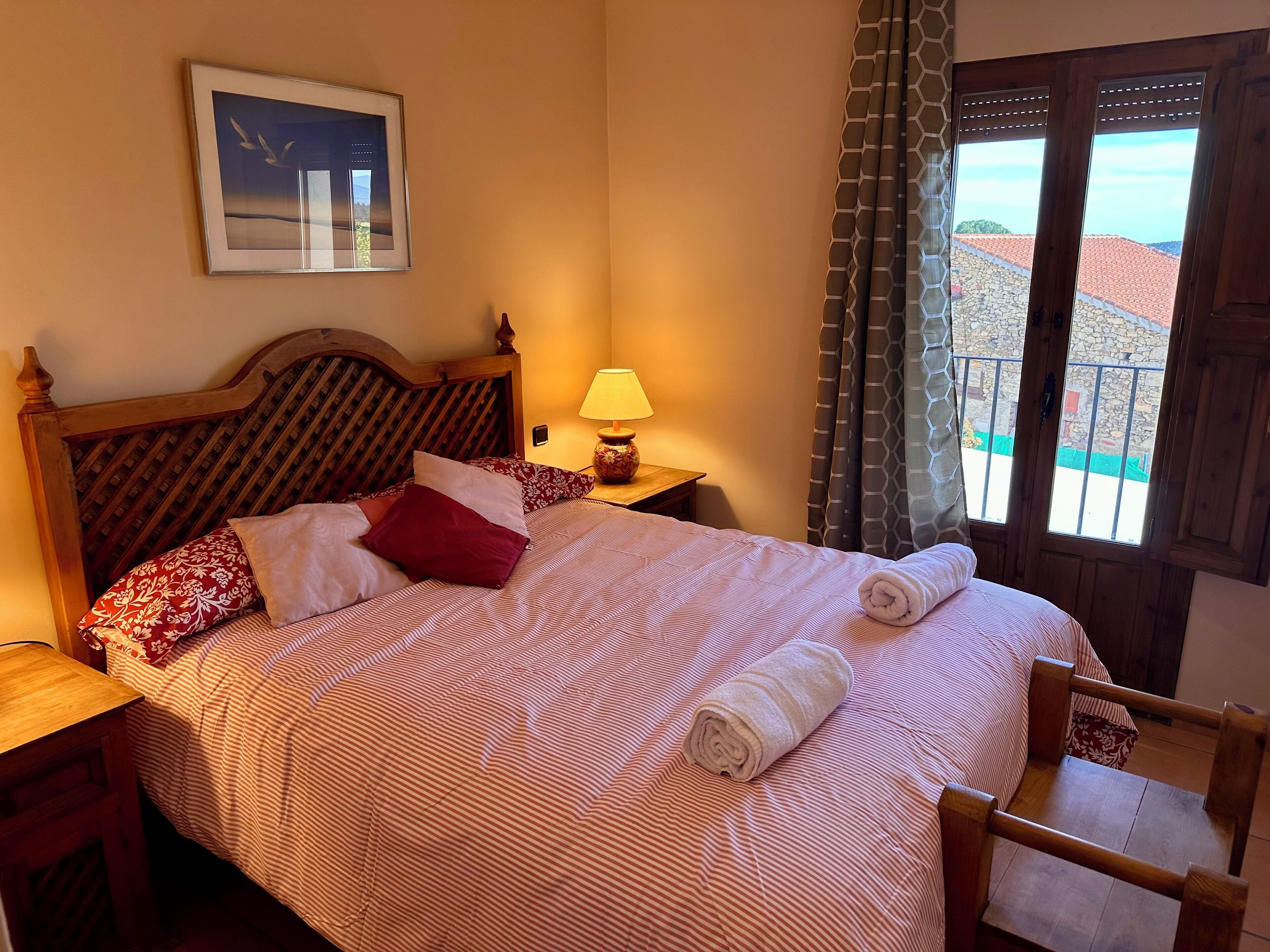 A neatly made bed with a striped bedspread, a wooden headboard, and a pillow with a floral pattern.