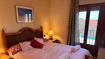 A neatly made bed with a striped bedspread, a wooden headboard, and a pillow with a floral pattern.