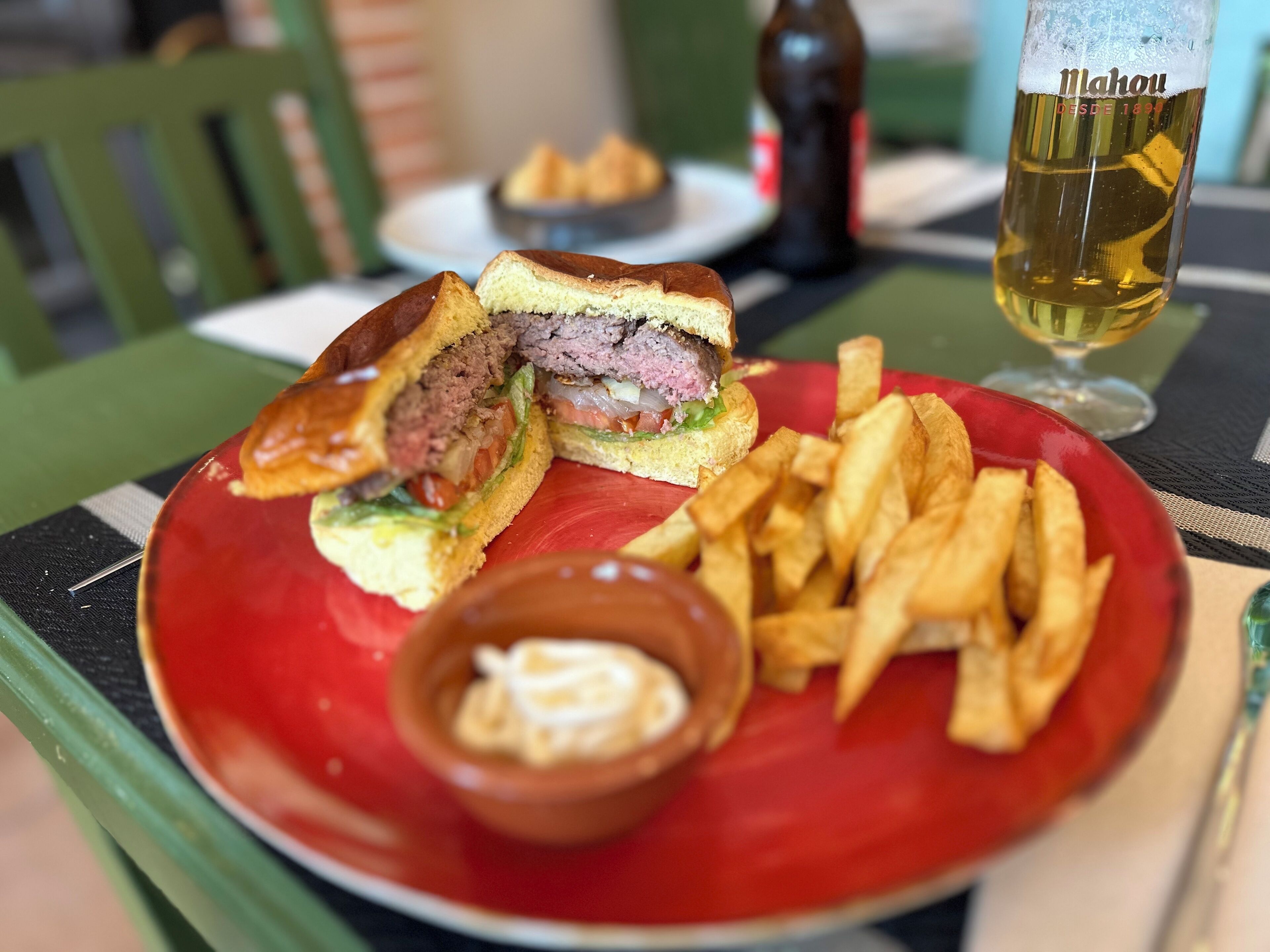 Un plato con un sándwich cortado por la mitad, una porción de papas fritas y un recipiente pequeño con salsa.