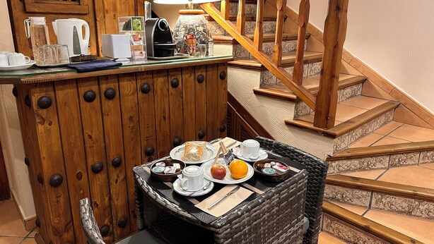 A cozy breakfast nook with a wicker table, a coffee machine, and a lamp. - Hotel Posada La Fragua (Pinuecar-Gandullas)