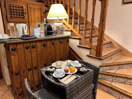 Un rincón desayunador acogedor con una mesa de mimbre, una cafetera y una lámpara.