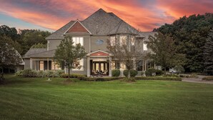 A large, two-story house with a prominent front porch and a well-maintained lawn.