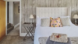 Ein Schlafzimmer mit Holzwand, einem weißen Bett und einem kleinen Nachttisch mit Lampe.