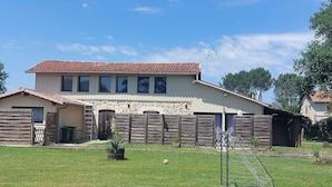 A two-story house with a stone facade, a fenced yard, and a soccer goal. - Gite de Charme Dans Grange Rénovée! (33830 - BELIN BELIET)