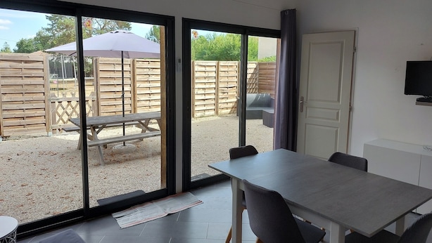 A modern room with a large sliding glass door leading to an outdoor patio area. - Gite de Charme Dans Grange Rénovée! (33830 - BELIN BELIET)