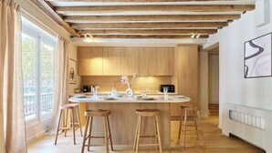 A modern kitchen with wooden cabinets, a central island with stools, and a view of the outdoors.