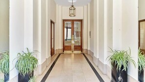 A hallway with a tiled floor, wooden doors, and potted plants.