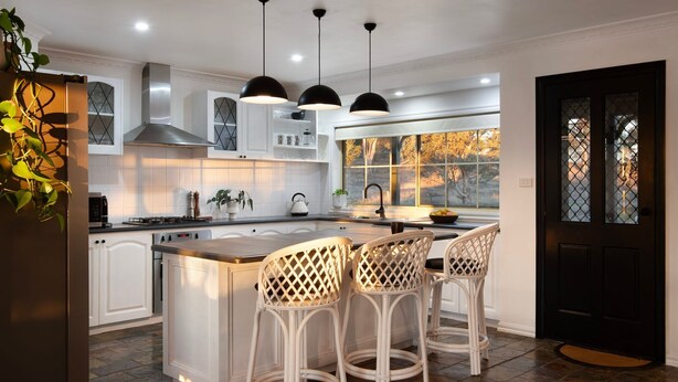 A modern kitchen with white cabinetry, a central island with bar stools, pendant lighting, and a view through a window. - Sunset Retreat-amaxing views over Mt Franklin (Franklinford)