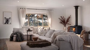 A cozy living room with a sofa set, a fireplace, and a large window with curtains. - Sunset Retreat-amaxing views over Mt Franklin (Franklinford)