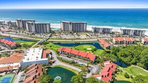 Un resort costero con varios edificios altos, un campo de golf y un puerto deportivo.