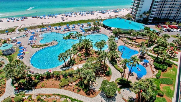 Un resort con varias piscinas, una playa y un edificio de gran altura.
