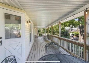 Une véranda avec une terrasse en bois, des chaises en métal et une table.