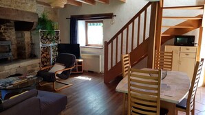 A cozy living room with a fireplace, wooden furniture, and a staircase leading upstairs.