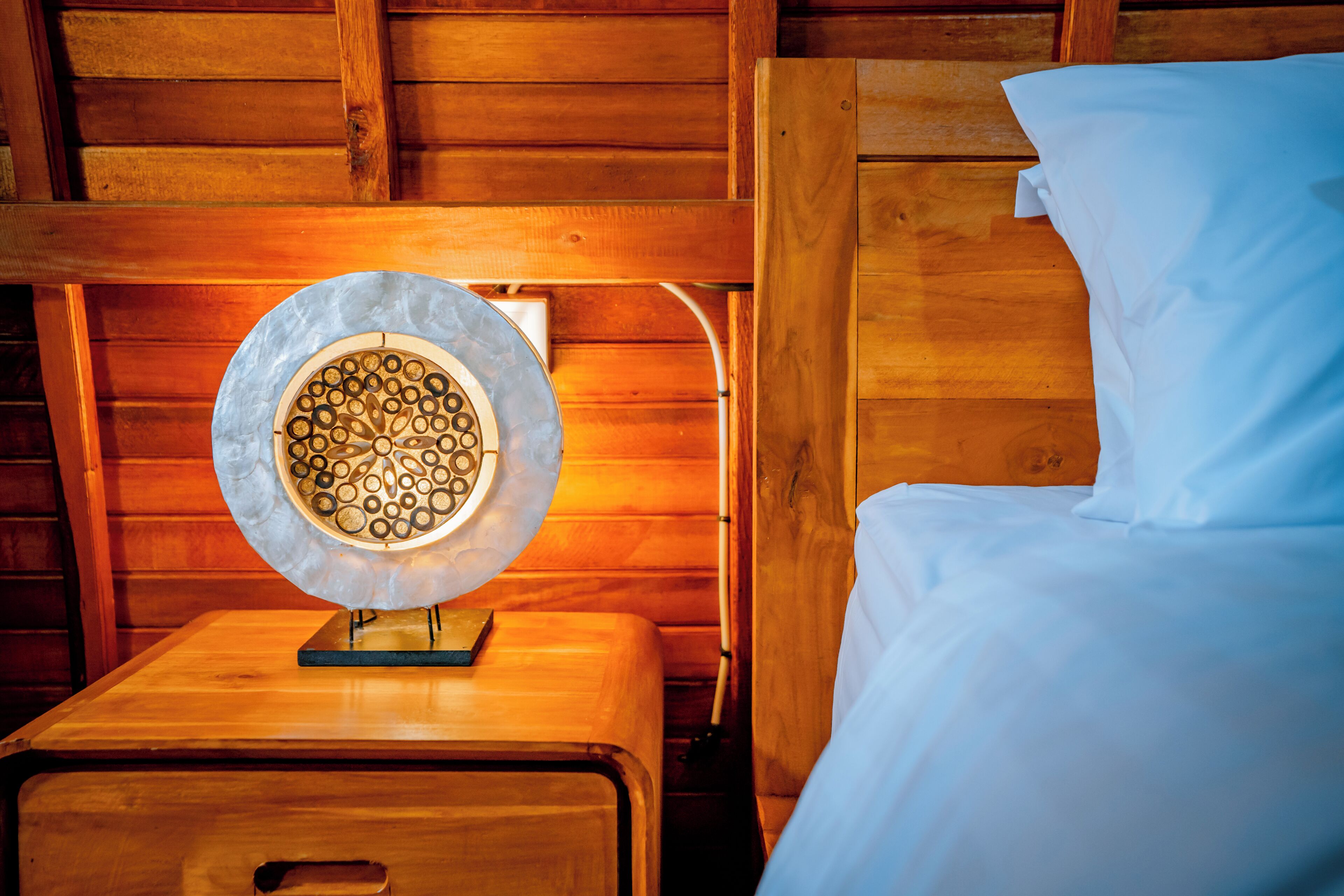 A wooden bedside table with a decorative plate and a small book.
