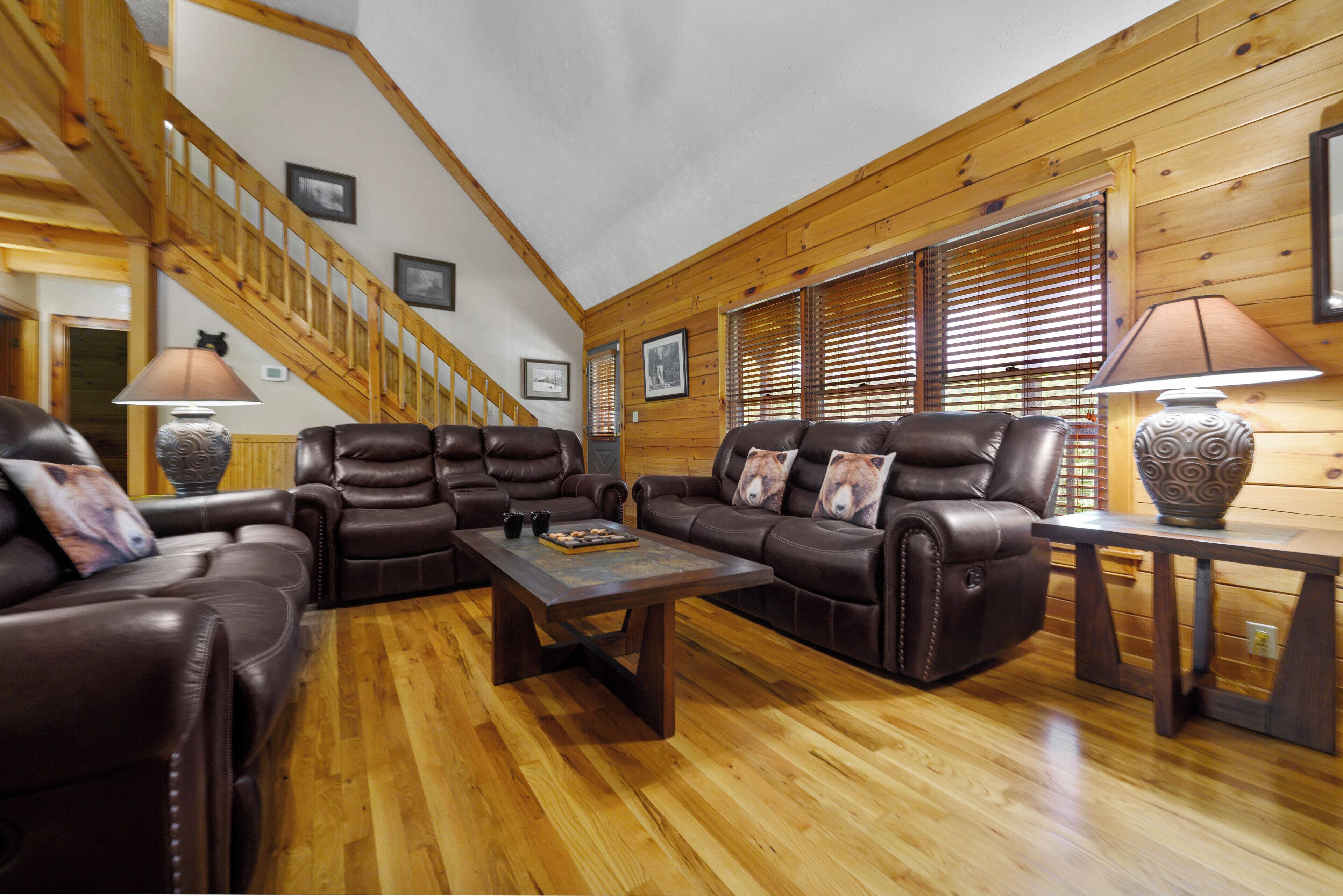 A spacious living room with leather sofas, a wooden coffee table, and a staircase leading to an upper level.