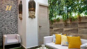 Una hall d'albergo con un divano bianco, un tavolino piccolo e una porta.