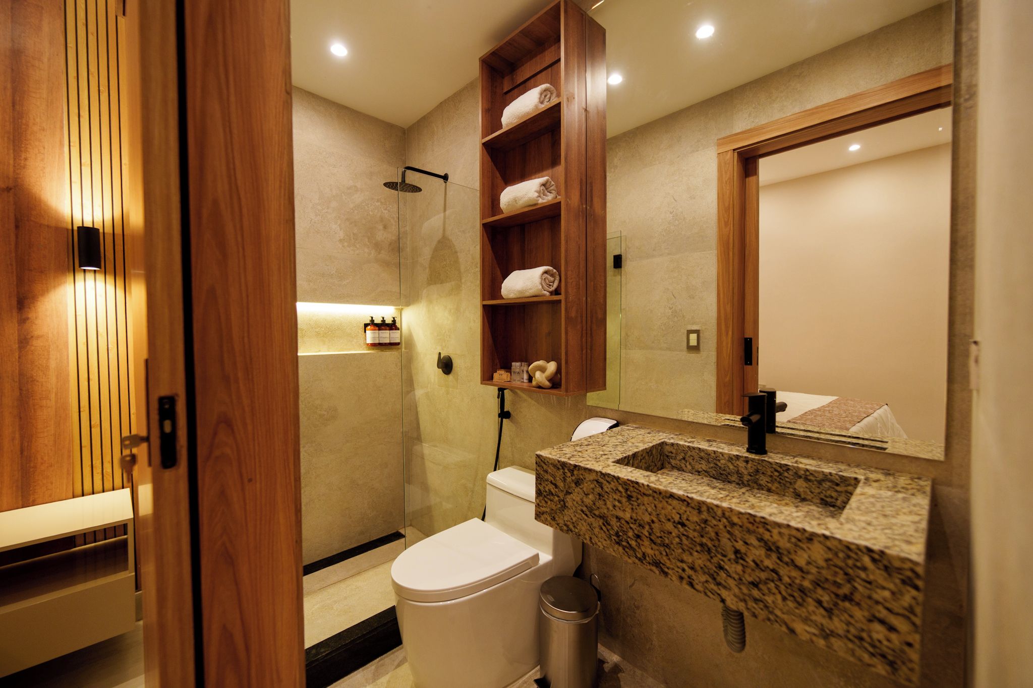 Un baño moderno con tocador de madera, inodoro, ducha y espejo.