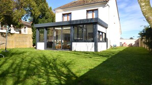 Ein modernes Haus mit Glaserker, einem gepflegten Rasen und blauem Himmel.