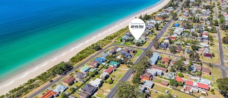 Vue aérienne d’une zone résidentielle côtière, avec des maisons, des routes et une plage.
