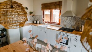 A kitchen with white cabinets, a wooden countertop, a hanging light fixture, a window with a bamboo blind, and a tiled backsplash. - Beautiful Family Home With Breathtaking View of the sea and the City of Kalamata (Perivolakia)