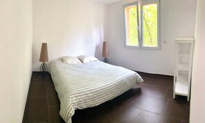 Cozy retreat with a single bed, striped bedspread, and a window for natural light.