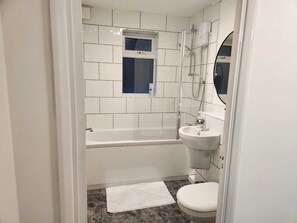 A small, modern bathroom with a bathtub, a sink, and a toilet.
