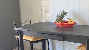 A dining area with a table and chairs, a basket of fruits, and a tiled wall. - Casa Albachiara a 500 Metri Dalla Spiaggia (Lavagna)