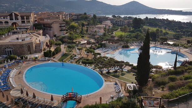 Ein Resort mit mehreren Schwimmbecken, darunter ein großes zentrales Becken, und Blick auf das Meer.