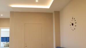 A modern living room with a dark blue sofa, a beige door, and a wall clock. - Freedom holiday house Positano (Sant'Antonio Abate)