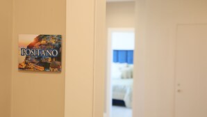 A hallway with a sign reading "POSITANO" and a glimpse of a bedroom with a bed and a blue curtain. - Freedom holiday house Positano (Sant'Antonio Abate)