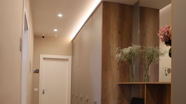 A hallway with wooden flooring, a white door, and a wooden shelf with a laptop and flowers. - Freedom holiday house Positano (Sant'Antonio Abate)