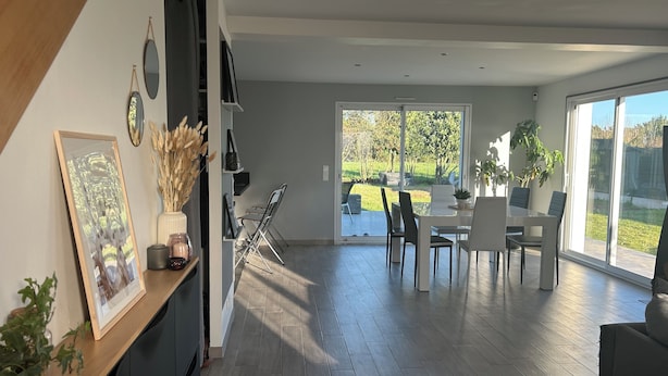 A modern kitchen with a dining area, large windows, and a view of the outdoors. - Maison Récente T5 Herbignac Proche Guerande (Herbignac)