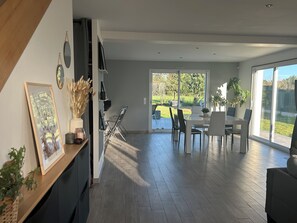 A modern kitchen with a dining area, large windows, and a view of the outdoors.
