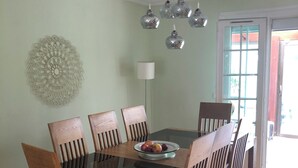 A dining area with a glass-top table surrounded by wooden chairs, a decorative wall piece, and a ceiling light fixture. - Spacious and modern 4 bedroom 2 bathroom House with garden ideal fir families  (Villejuif)