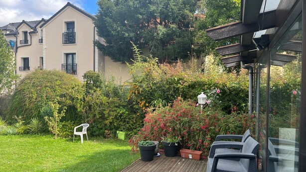 A wooden deck with outdoor furniture, a white chair, and potted plants. - Spacious and modern 4 bedroom 2 bathroom House with garden ideal fir families  (Villejuif)