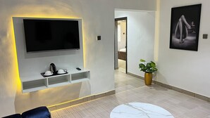 A modern hotel lobby with a flat-screen TV mounted on the wall, a coffee station, a potted plant, and a marble-tiled floor. - Apartment 550 (Abuja)