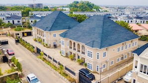 A large, multi-story building with a prominent blue roof, surrounded by other residential buildings and greenery. - Apartment 550 (Abuja)