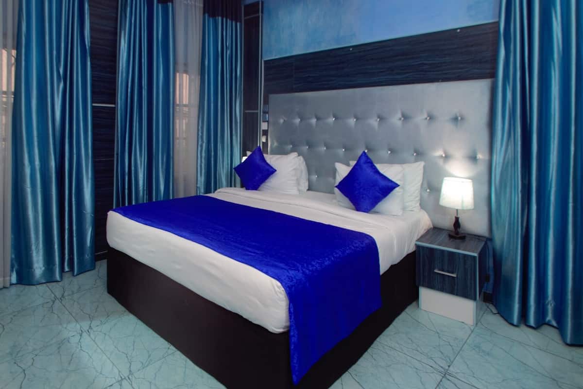 A modern hotel room with a large bed, a nightstand, and a headboard with a tufted design.