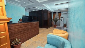 A reception area with a wooden reception desk, a blue wall, and a potted plant. - Apartment 550 (Abuja)