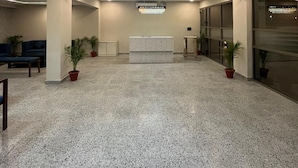 A spacious lobby with a large chandelier, a reception desk, and potted plants. - Tatvam Villa (Sohna)
