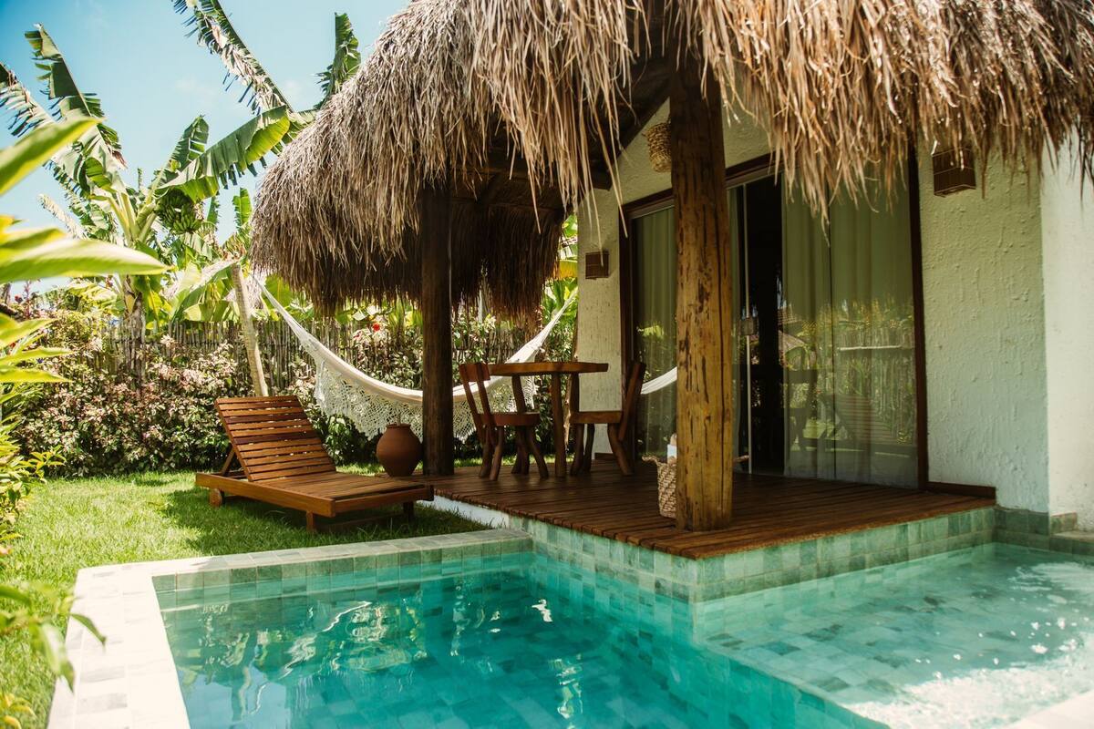 A poolside area with a wooden deck, a hammock, and a table.