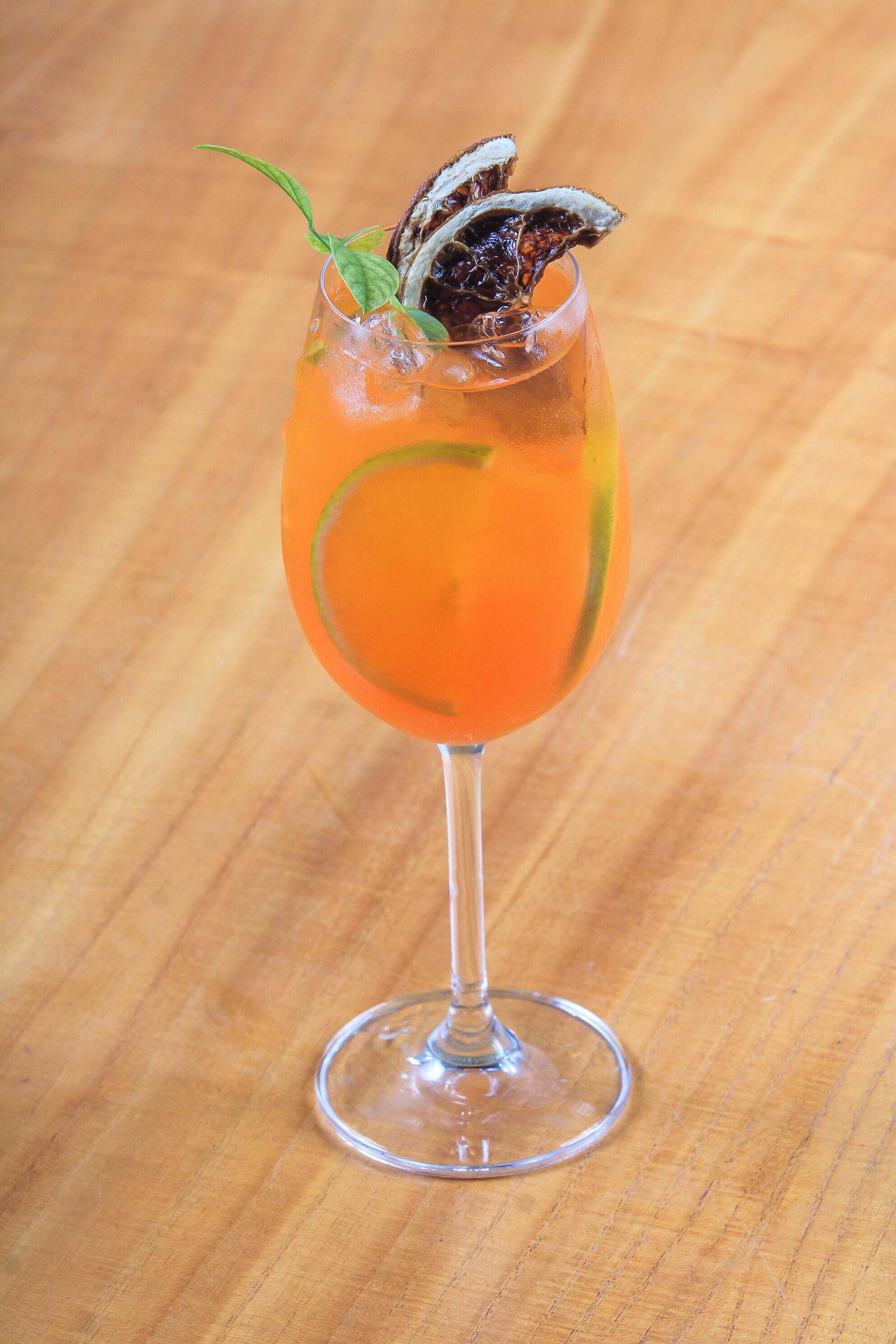 A cocktail in a stemmed glass with a garnish, set on a wooden surface.