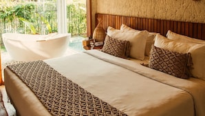 Une chambre spacieuse avec un grand lit, une vue sur un jardin et une baignoire.