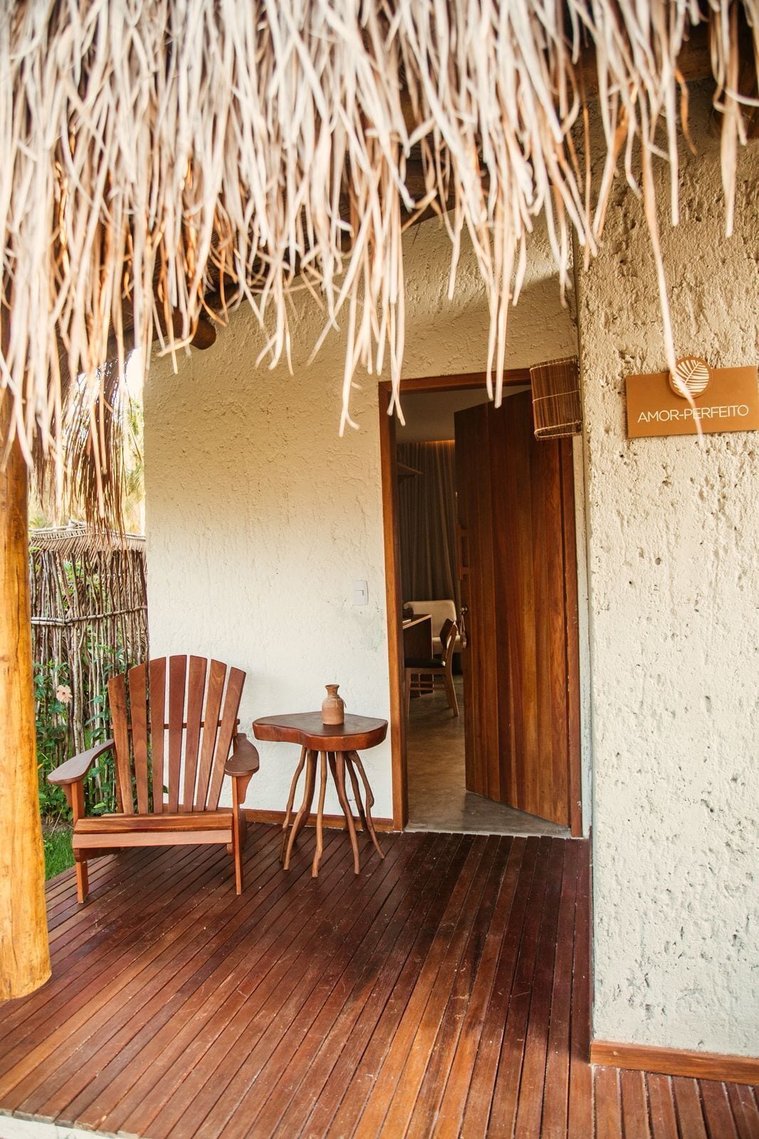 A wooden deck with a thatched roof, a wooden chair, and a small table.