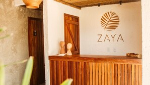 Un espace d’accueil doté d’un comptoir en bois, d’un logo placé au-dessus et d’un plafond au style rustique.
