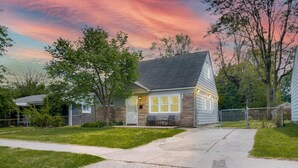 Una casa a un piano con portico anteriore, un piccolo garage adiacente e un prato curato.