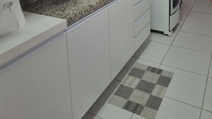 A modern kitchen with white cabinets, a granite countertop, a built-in oven, and a stainless steel sink. - Apto Próximo ao Pátio do Forró (Maurício de Nassau Caruaru)