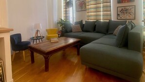 A living room with a sectional sofa, a small table, a blue chair, and a lamp.