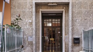A stone building entrance with a metal gate, a mailbox, and a number plaque. - Light Apartment in Albaro (Genoa)