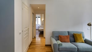 A hallway with a grey sofa, two pillows, and a floor lamp. - Light Apartment in Albaro (Genoa)